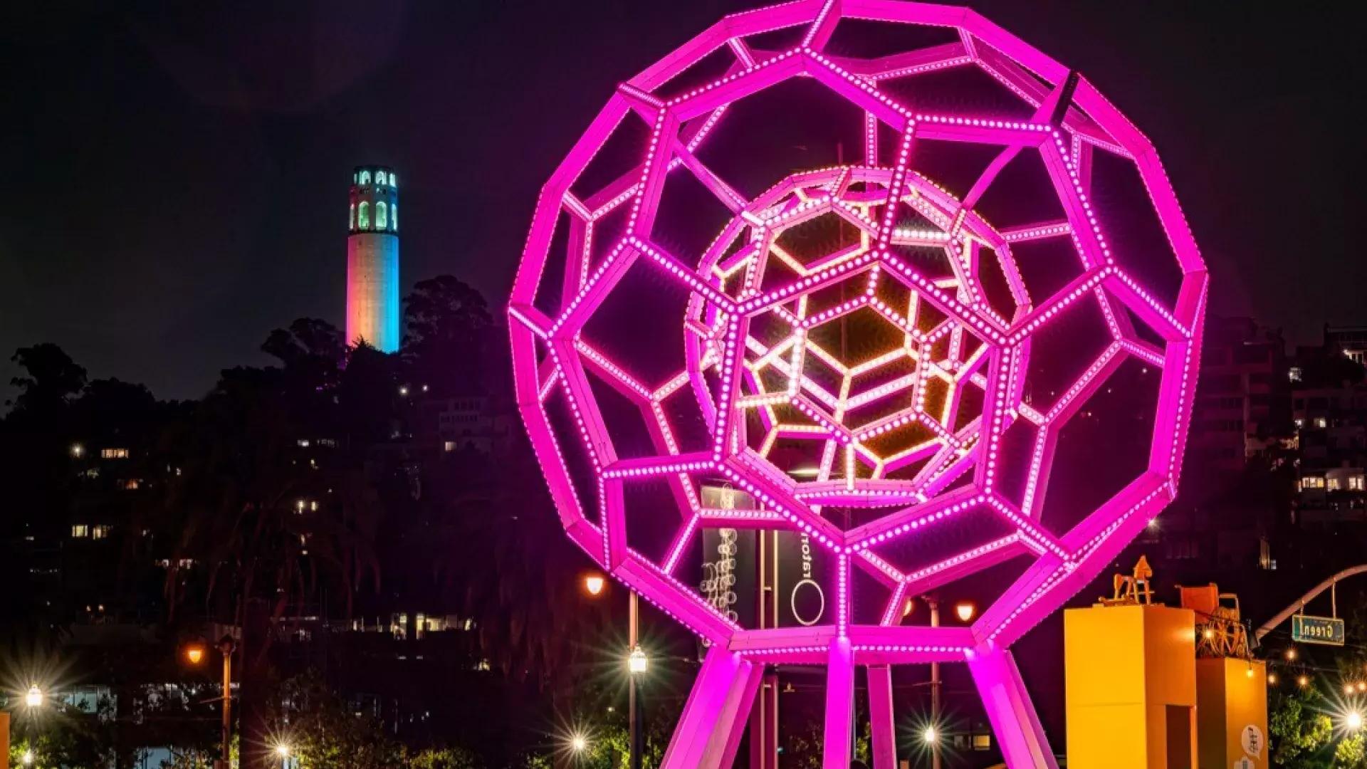 Buckyball shines outside the Exploratorium, with Coit Tower in the background