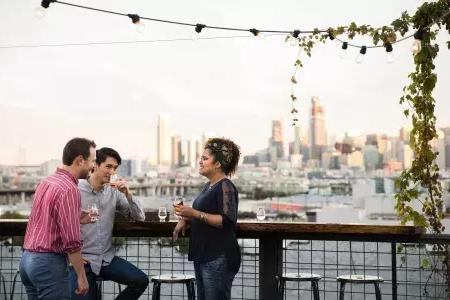 三people聚集各地an甲板outdoor table on the roof of主管股Distilling in 贝博体彩app, 加州.